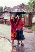 Two girl children with umbrella on a rainy day in Kottayam