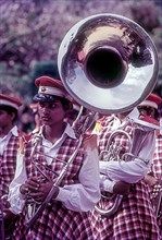 A girl in a music troop holding a big trumpet in a carnival