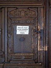 Portal of the Catholic parish church of St. George with sign 'Please always close the bags