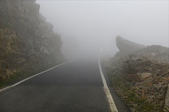 Low clouds on winding mountain road pass at the top of Colle del Nivolet
