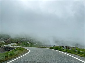 Low clouds over winding mountain road Pass road to Colle del Nivolet