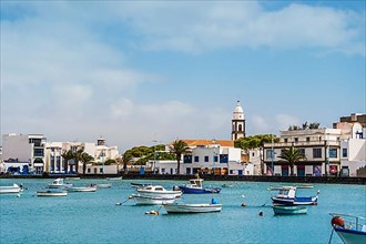 Beautiful quay with historic architecture and boats on blue water in Arrecife