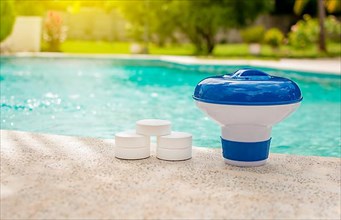 A pool float and chlorine tablets on the edge of a swimming pool. Tablets with chlorine dispenser for swimming pools. Chlorine tablets with dosing float
