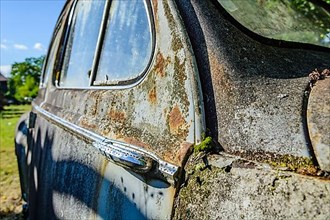 Old car rolled for scrapping in a meadow. Alsace