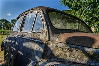 Old car rolled for scrapping in a meadow. Alsace