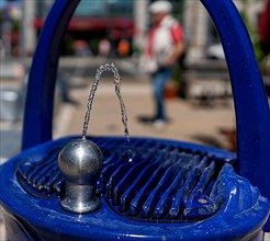 Blue fountain with drinking water dispenser on a public square