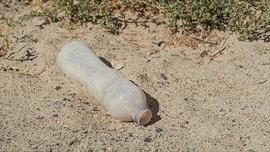 Close-up of plastic bottle in the desert. Plastic pollution in sandy desert. Egypt