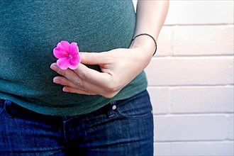 33 weeks pregnant woman holding a flower over her belly