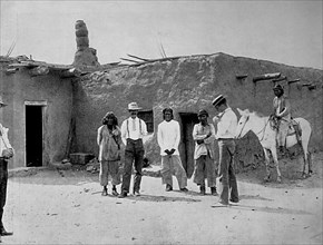 Descendants of the ancient Aztecs and descendants of the Spanish conquistadors in front of an adobe house in New Mexico