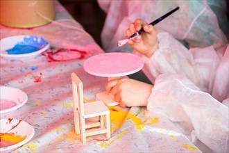 Young children decorating handmade wooden chair
