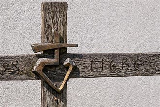Wooden cross with metal emblem and the word Love carved in wood
