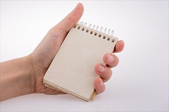 Hand holding a spiral notebook on a white background