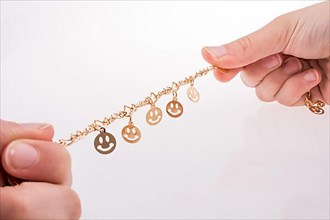 Golden color smileys arrayed on a chain in hand