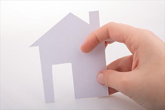 Hand holding a paper house on a white background