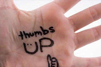 Thumbs up written on hand palm on a white background
