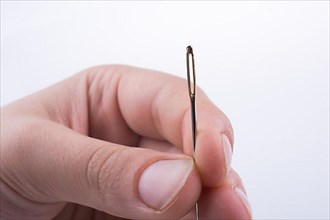 Hand holding a needle on a white background
