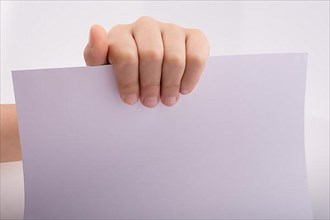 Hand holding a white sheet of paper on a white background