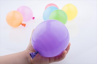 Hand holding a Colorful small balloon with colorful baloons on the white background