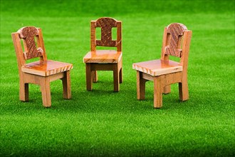 Brown color wooden toy chair on artificial grass