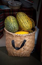 Green speckled melons in a straw basket in the view