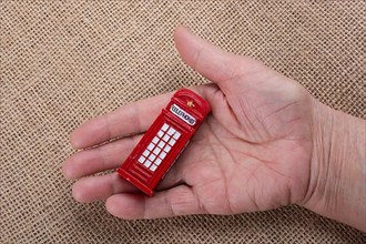Hand holding a phone booth on a brown background
