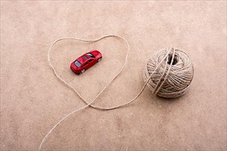 TRed toy car and a spool of thread form a heart shape on background