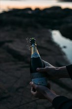Opening a bottle of champagne on the beach