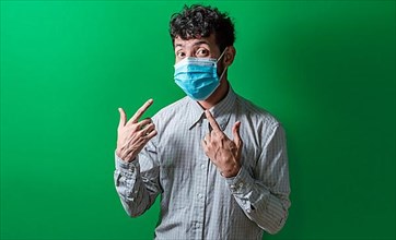 Isolated man wearing double surgical mask pointing to them with thumbs, Person wearing double mask with thumbs up. Concept of the double use of surgical mask