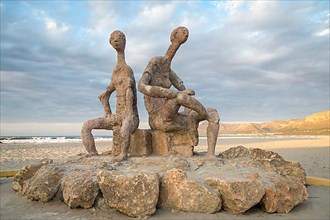 Sculptures by Joan Bennassar on beach promenade with sandy beach Playa Sa Canova in Son Serra de Marina, Serres de Llevant mountains in the back