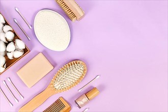Eco friendly wooden beauty and hygiene products like comb and soap arranged on violet background,