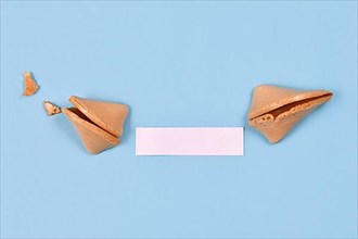 Open fortune cookie with note without text on blue background,