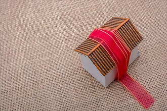 Pink band wrapped around a model house on a brown background,