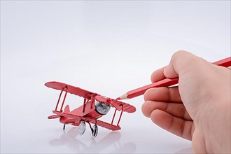 Red color pen in touch with little metal model airplane,
