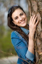 Woman leaning against tree trunk,