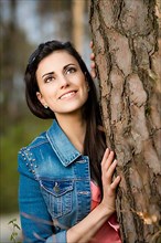 Woman leaning against tree trunk,