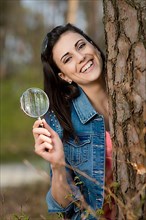 Woman looks at tree trunk under the magnifying glass,