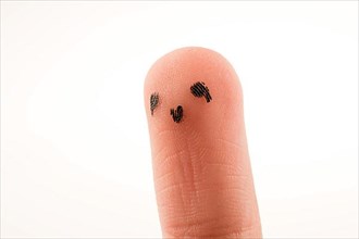 Black dots forming a face on the fingertip,