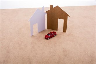 Paper house and a model car on a canvas background,