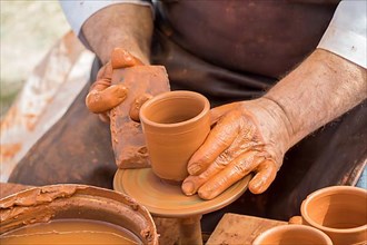 Potter`s hands shaping up the clay of the pot,