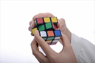 Child holding a Rubik's cube in hand on a white background,