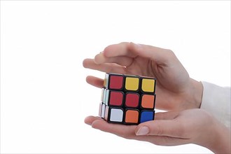 Child holding a Rubik's cube in hand on a white background,