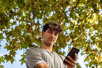 Low angle of a young man holding his smartphone, serious