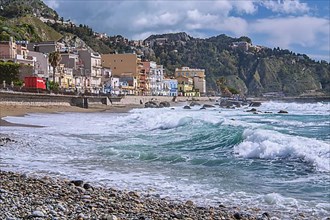 Sea surf in front of the promenade with Taormina on the hill, Giardini-Naxos