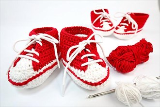 Baby shoes or crochet shoes in red and white isolated against a white background,