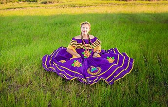 Nicaraguan woman in traditional folk dress sitting on the grass in the field, Portrait of Nicaraguan woman wearing national folk dress