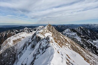 Rocky snowy ridge, summit of Ammergauer Hochplatte with summit cross