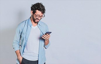 Handsome man smiling and using mobile phone isolated, People smiling and looking at ad on cell phone. Person in glasses smiling using smartphone on isolated background