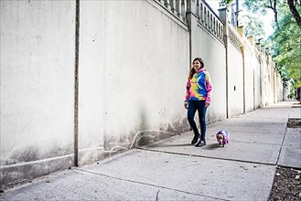 Latin woman walking her dog, both dressed alike. Grey background. Copy space