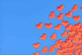Red heart shaped confetti in corner of blue background with empty copy space,