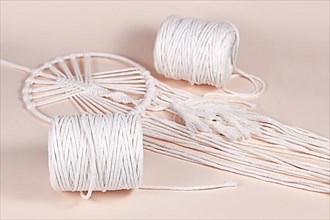 Cream white cotton macrame cord used for DIY decoration object on beige background,